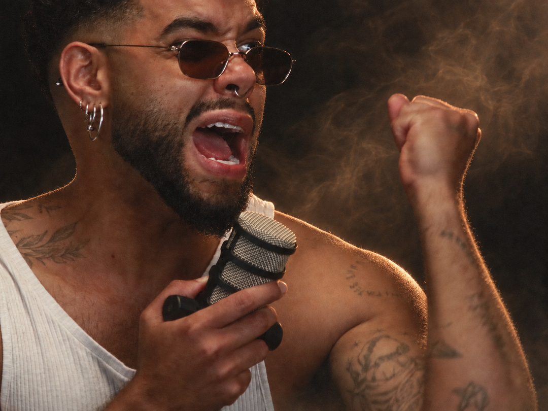 Saulo de óculos escuros, cantando com o microfone em uma mão e o outro punho levantado.