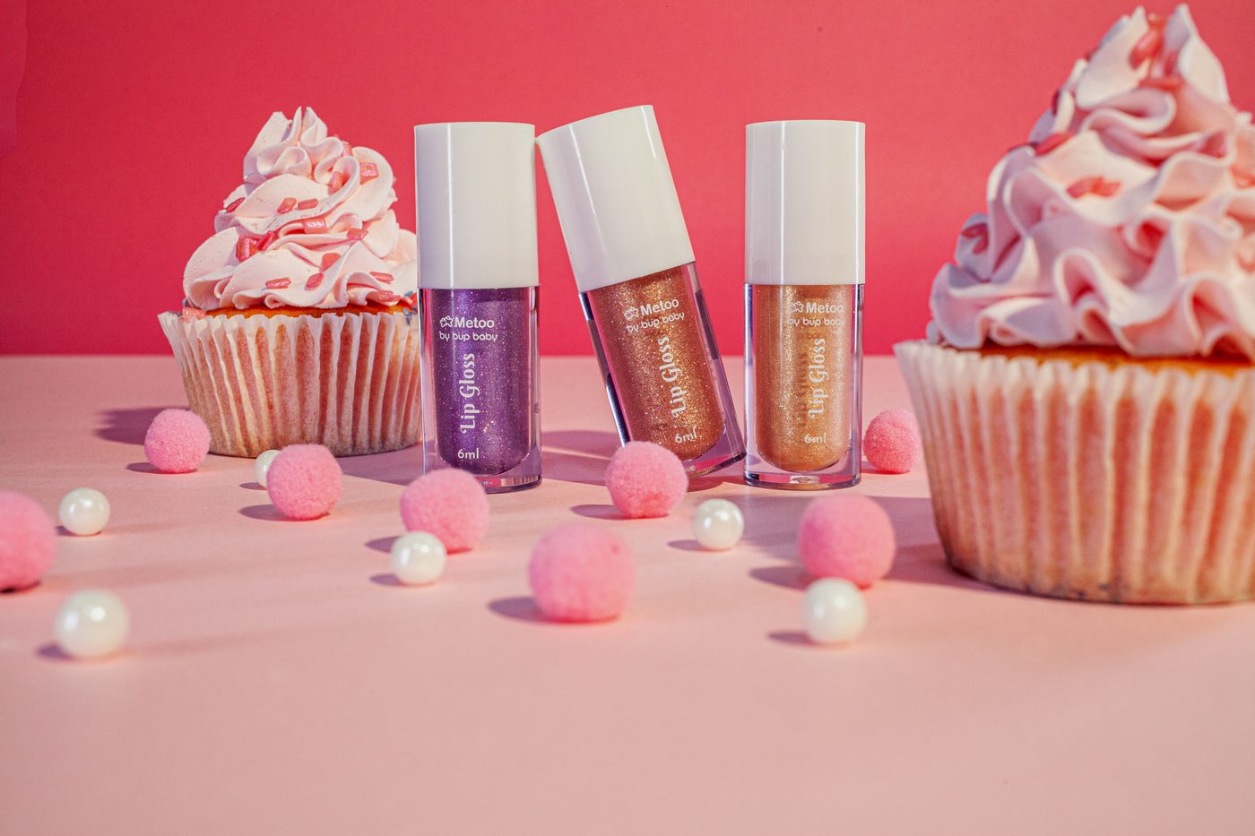 Três frascos da linha Metoo entre cupcakes rosa, ambientação de feed em fotografia de produto
