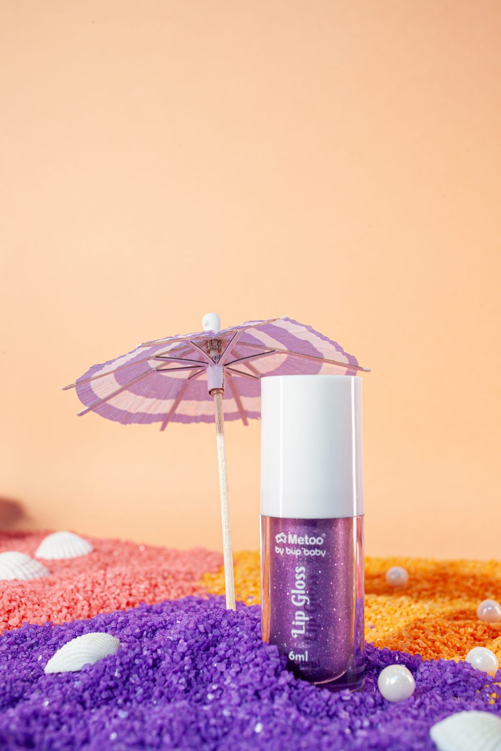 Frasco roxo do gloss Metoo em close na areia roxa, foto de produto com luz quente